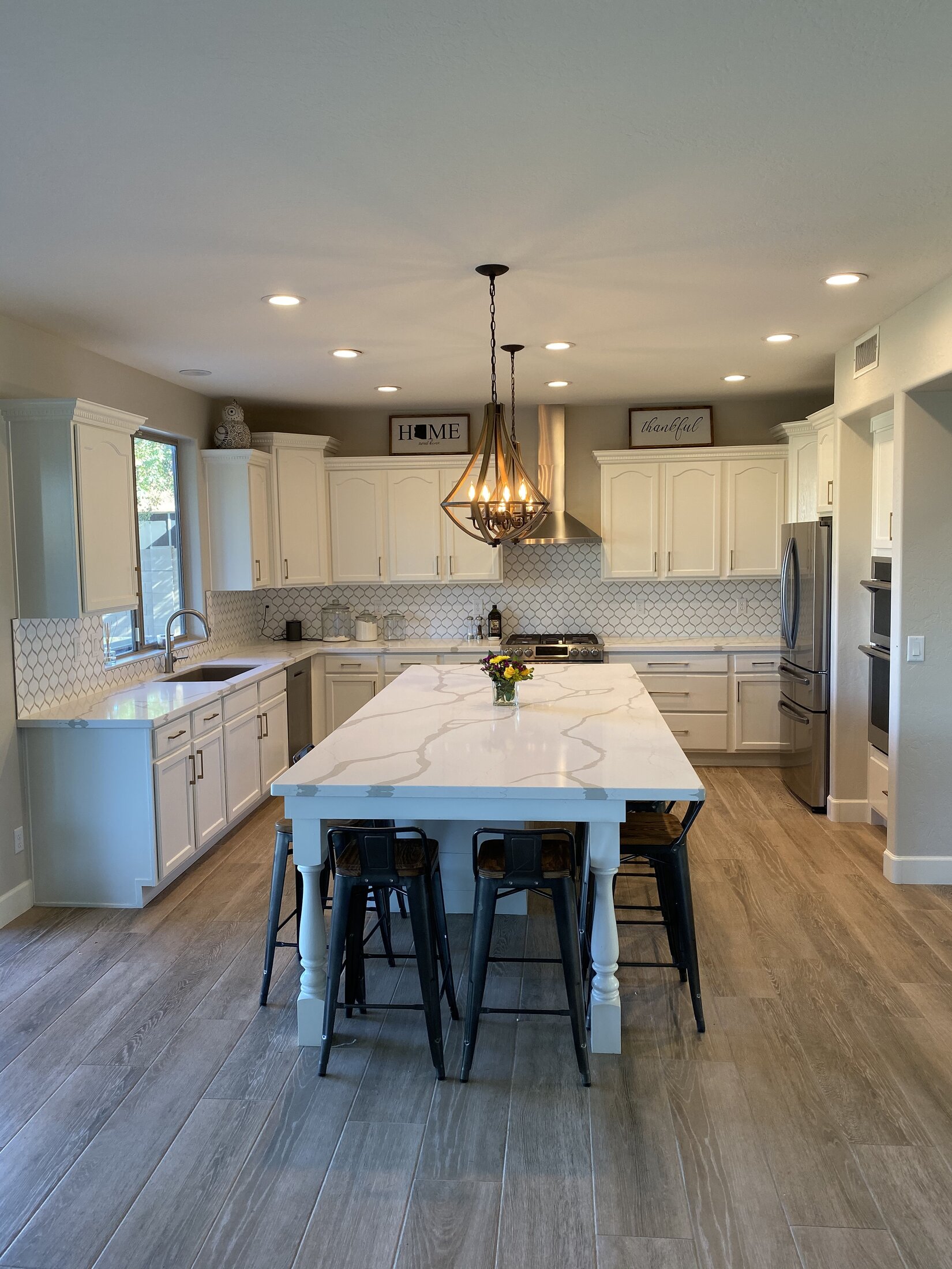 White farmhouse kitchen remodel with oversized marble island and pendant lighting, West Valley AZ