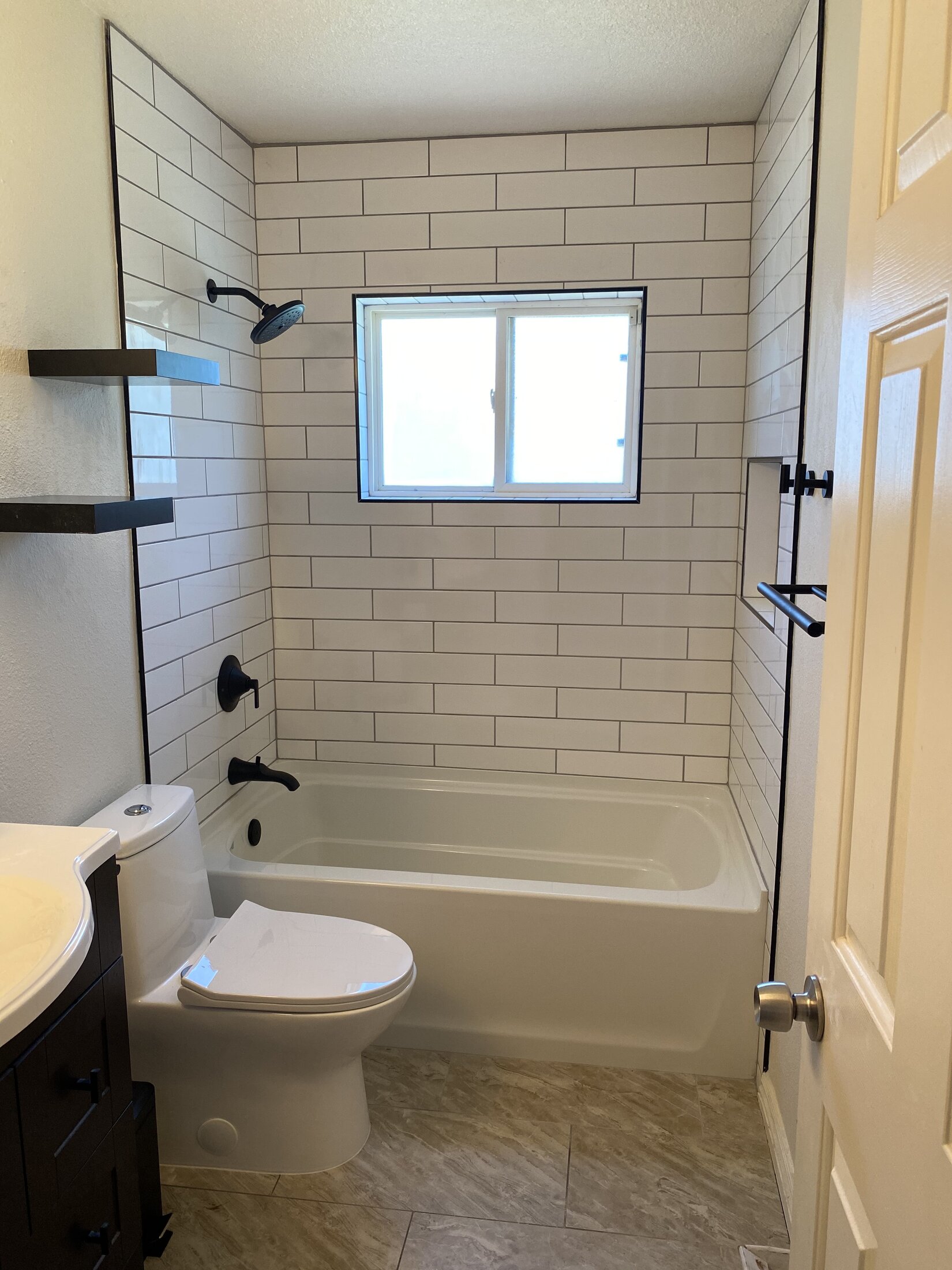 Guest bathroom remodel with white subway tile, matte black fixtures, and soaking tub
