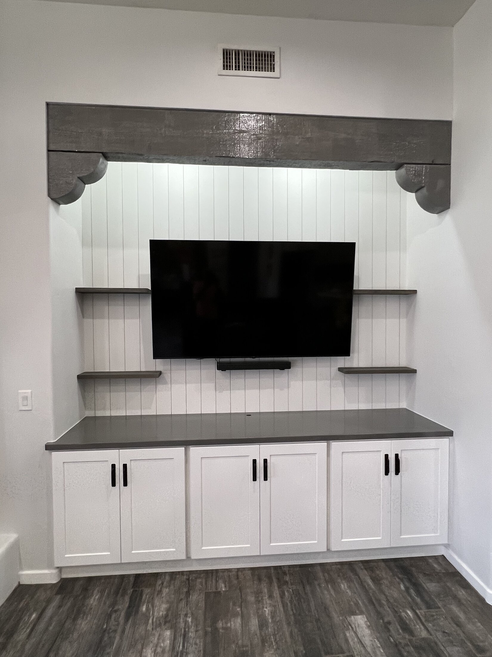 Finished white shiplap media wall with mounted TV, floating shelves, and cabinetry, JBS remodel