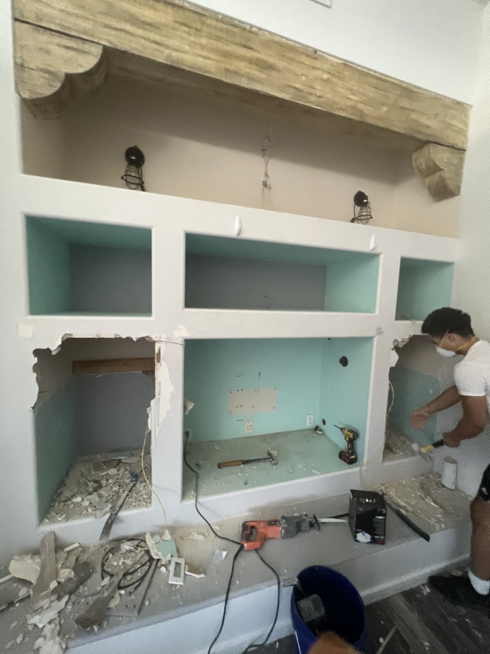 Entertainment center built-in mid-demolition with drywall removed and framing exposed, JBS remodel